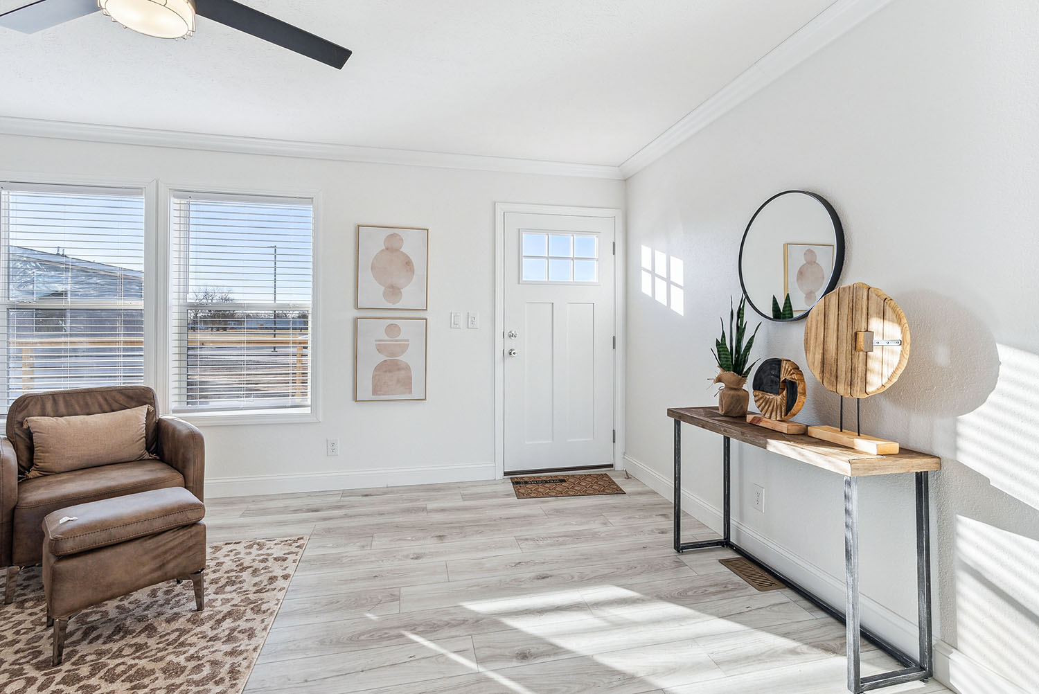 The entryway into a home looking towards the white closed door. There is a small table with decor and a mirror on the wall.